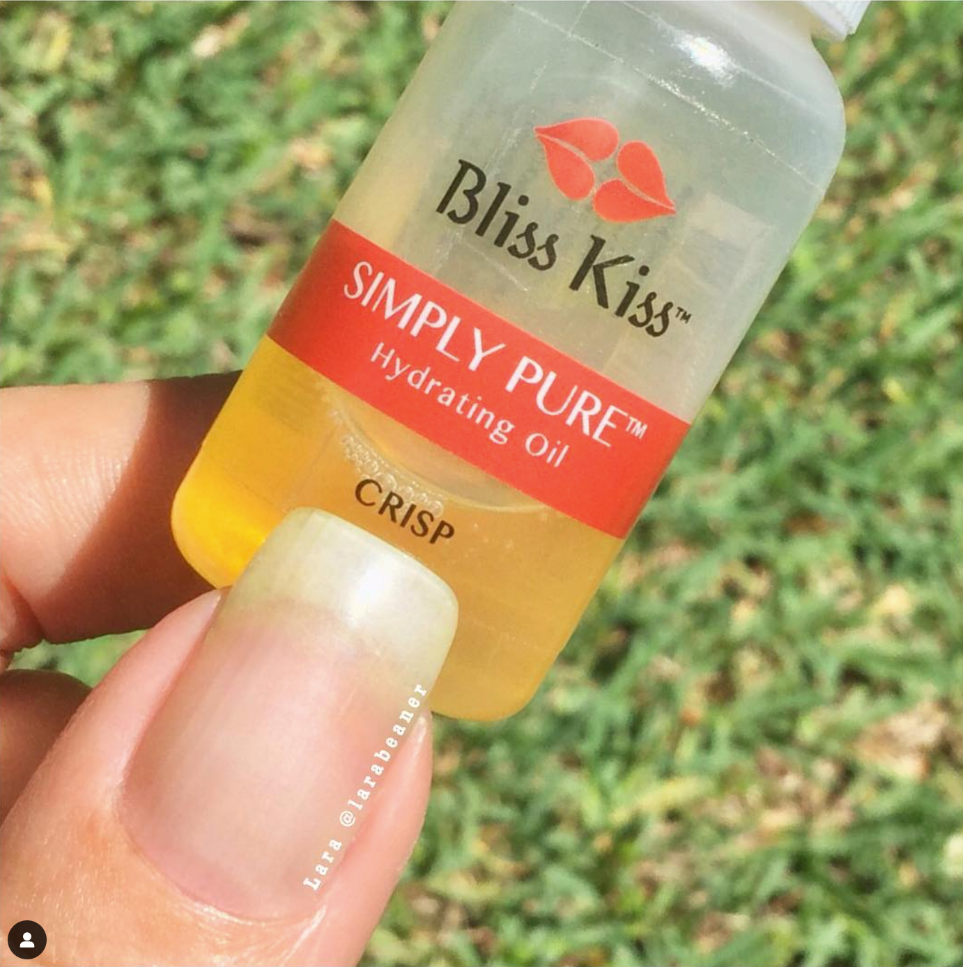 Image shows a Nail holding a Simply Pure hydrating oil bottle in the crisp scent. the nail looks long, strong, and healthy. 
@ Laurabeaner