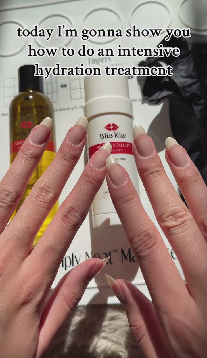 "today I'm gonna show you how to do an intensive hydration treatment" Below is a set of well manicured, nourished, and healthy hands. the nails are clean and unpolished. Behind the hands are Bliss kiss lotion stick and a bottle of bliss kiss oil